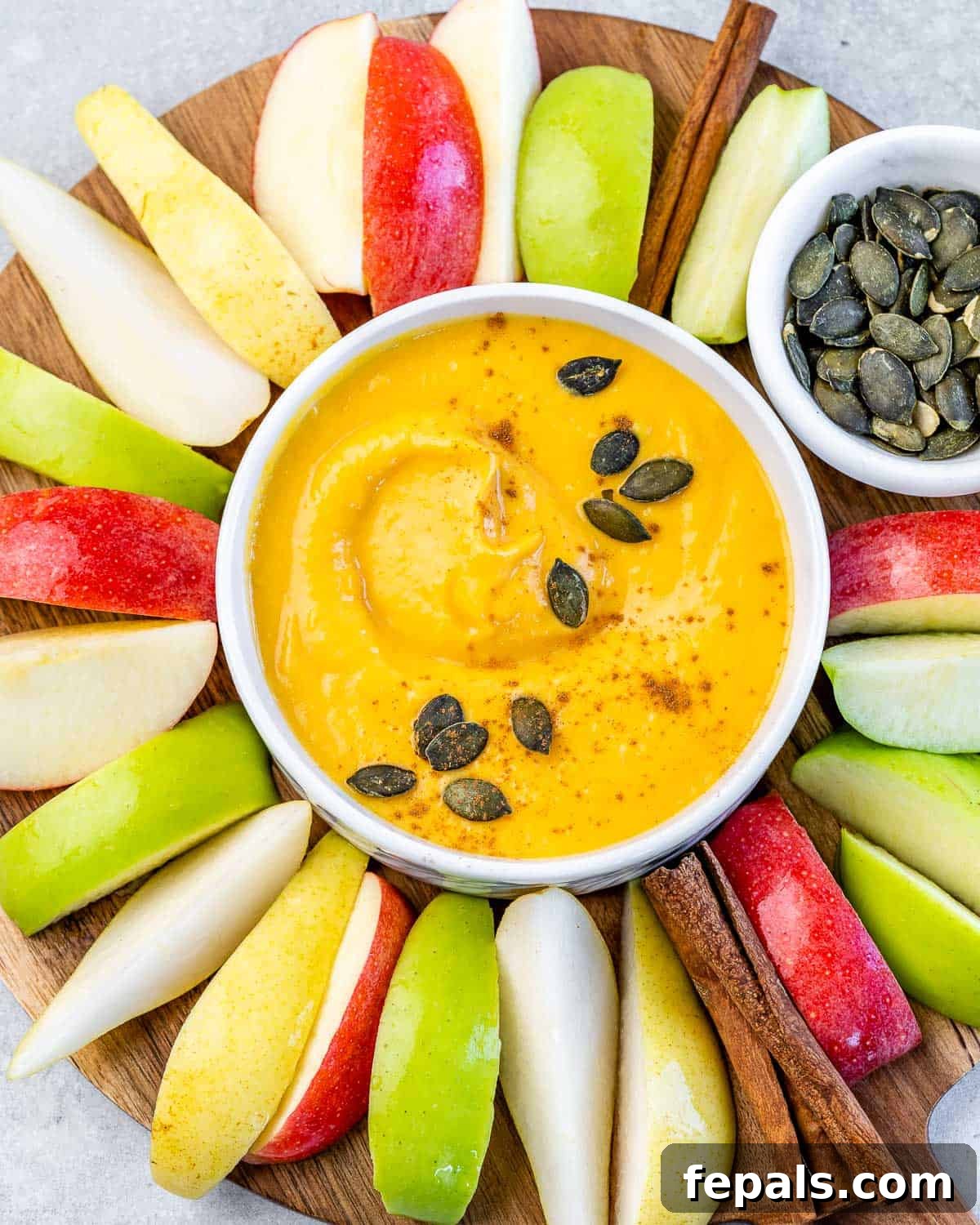 Pumpkin pie dip in a white bowl served with apple slices.