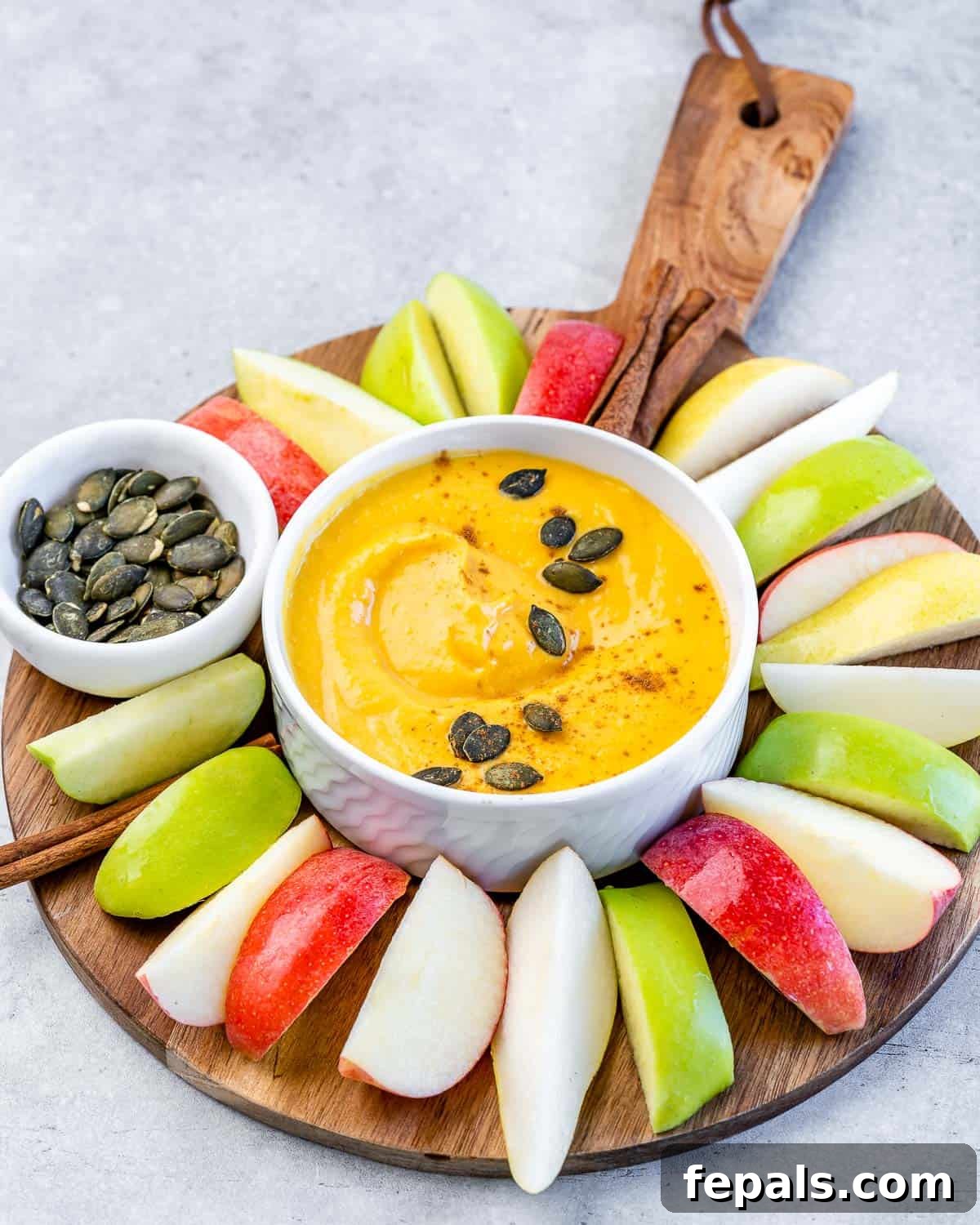 Pumpkin dip in a small white bowl with apple slices.