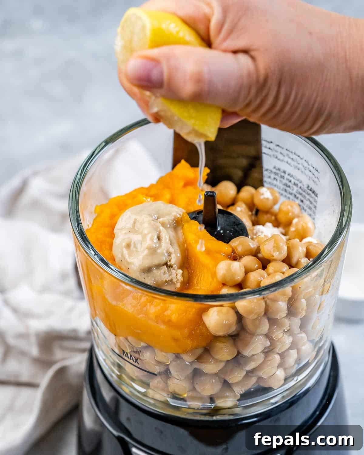 Spiced Pumpkin Hummus 6 Squeezing lemon juice into a food processor with chickpeas and pumpkin puree.