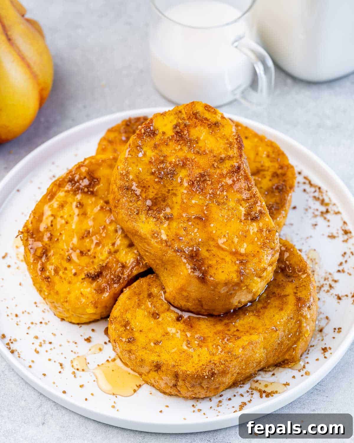 Side shot of 4 french toast on a plate with a drizzle of maple syrup over the French toast.