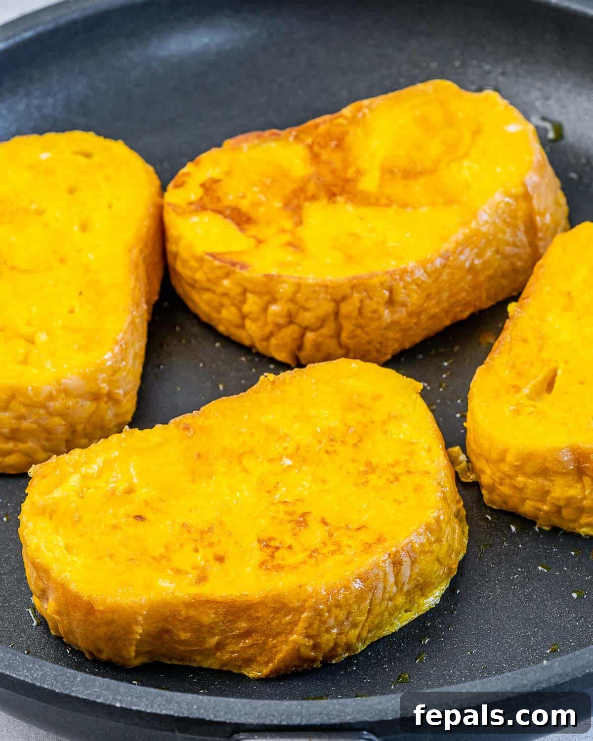 Pumpkin French toast cooking on a pan.