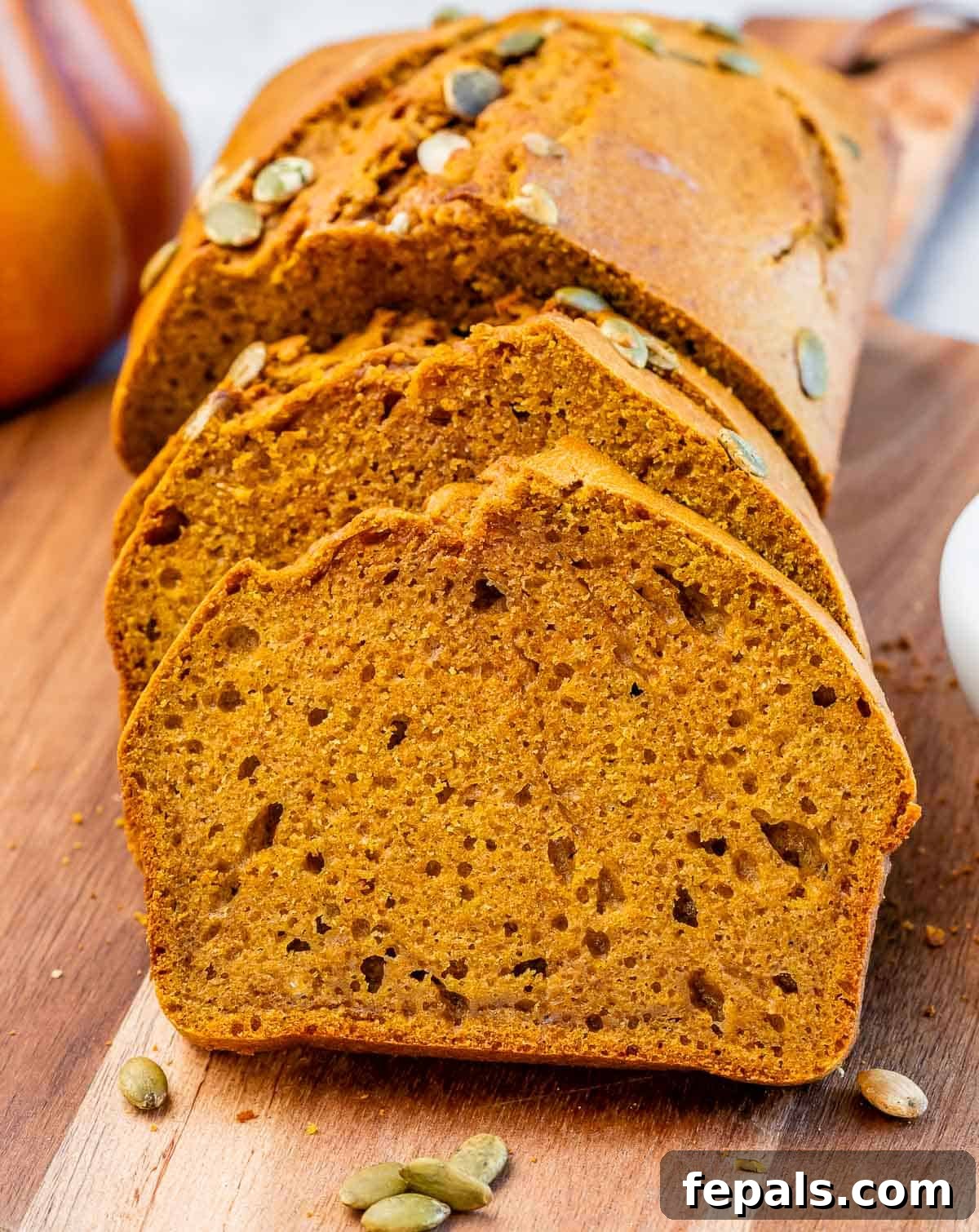 Sliced pumpkin bread topped with pumpkin seeds, arranged beautifully on a serving dish.