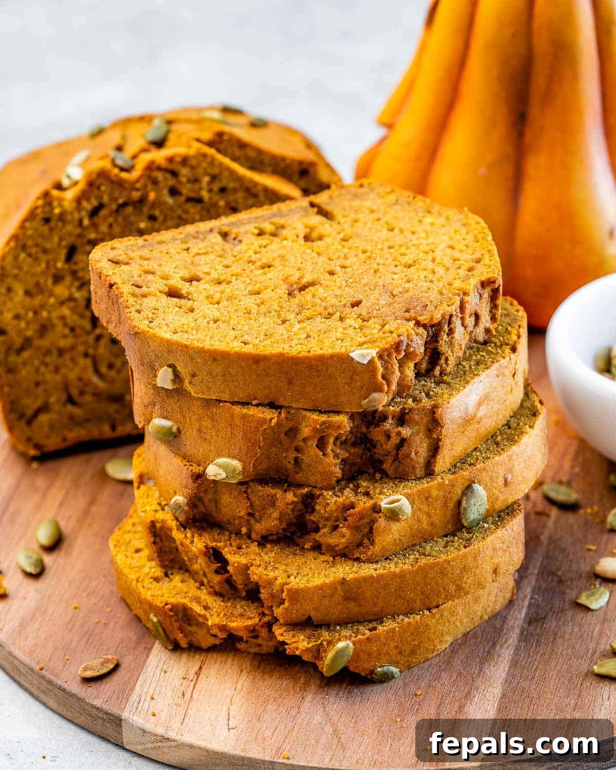 Slices of healthy pumpkin bread stacked on a wooden cutting board, ready to serve.