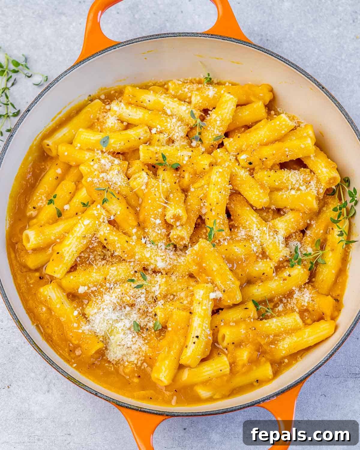Creamy pumpkin pasta served in a large pot, with a serving spoon, ready for a family meal.
