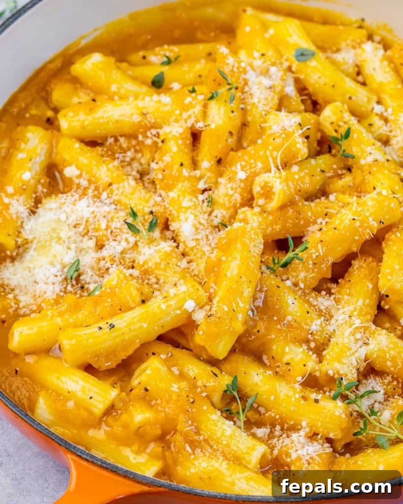 Side shot of creamy orange-colored pumpkin pasta in a rustic serving dish, ready to be enjoyed.