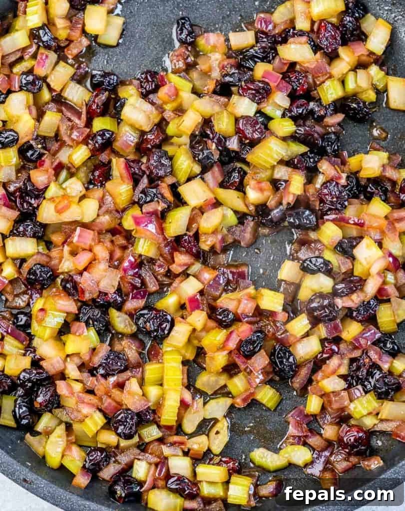 Golden Herb Roasted Sheet Pan Turkey Breast 6 Onions, celery, garlic, and cranberries cooking in a pan, absorbing flavorful liquids.