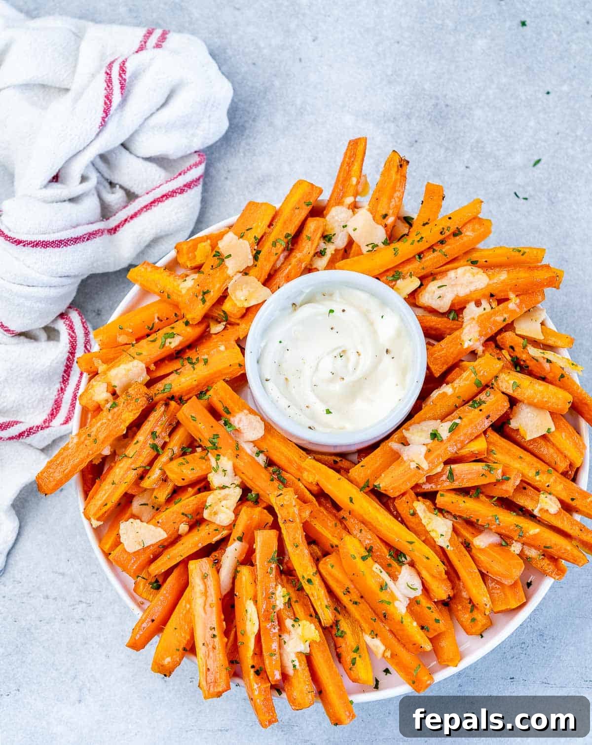 Parmesan Crusted Carrot Fries 2 Top view of carrot fries in a round plate with a small bowl of dipping sauce in the middle, ready to be enjoyed.