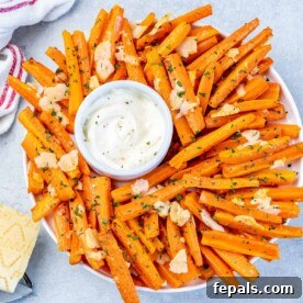 Parmesan Crusted Carrot Fries 12 top view of carrot fried in a round plate with a small bowl of dipping sauce in the middle