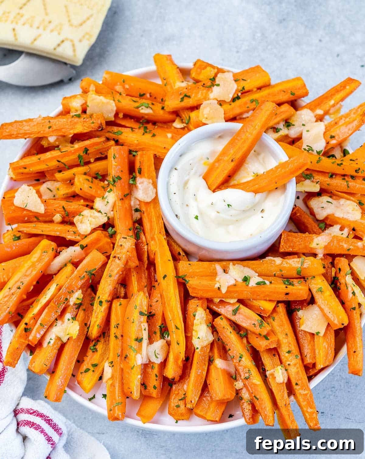 Parmesan Crusted Carrot Fries 3 Carrot fries being dipped into a creamy white sauce, highlighting their crispy texture.