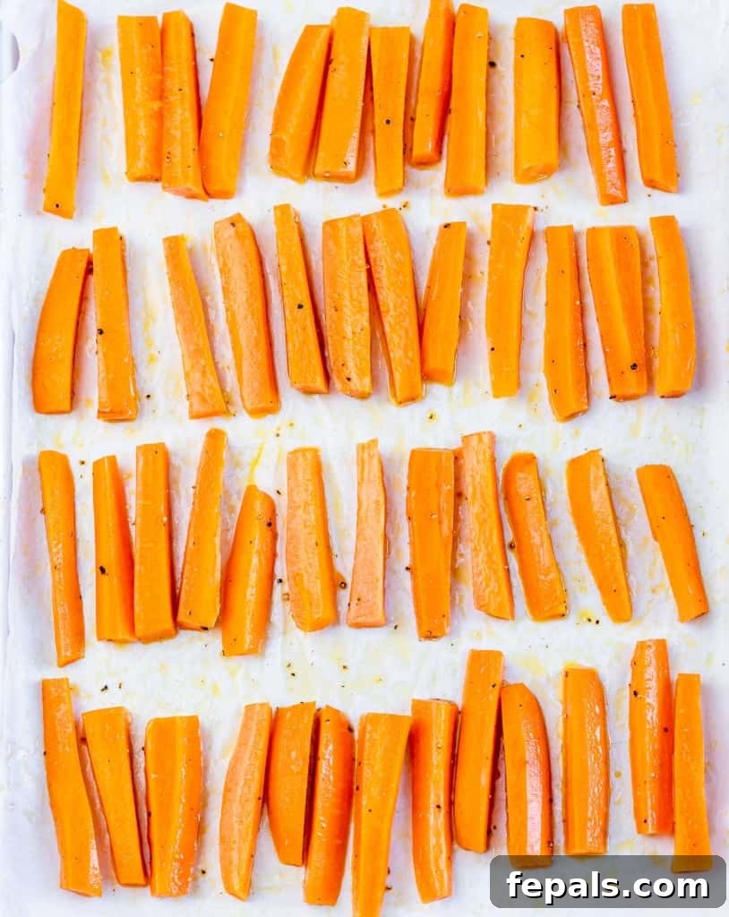 Parmesan Crusted Carrot Fries 7 Carrot fries roasting on a parchment-lined pan, showing early stages of browning.