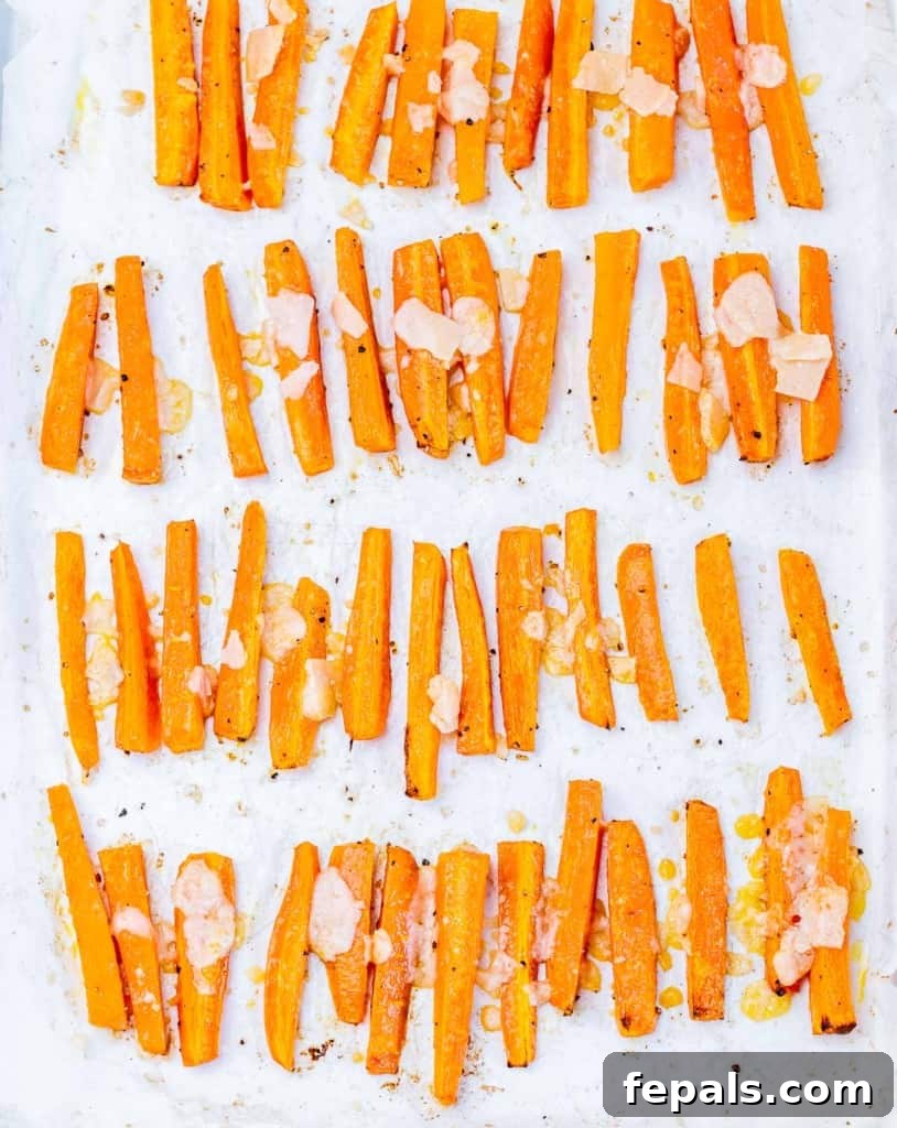 Parmesan Crusted Carrot Fries 8 Freshly shaved Parmesan being tossed with roasted carrot fries, adding a cheesy, savory coating.