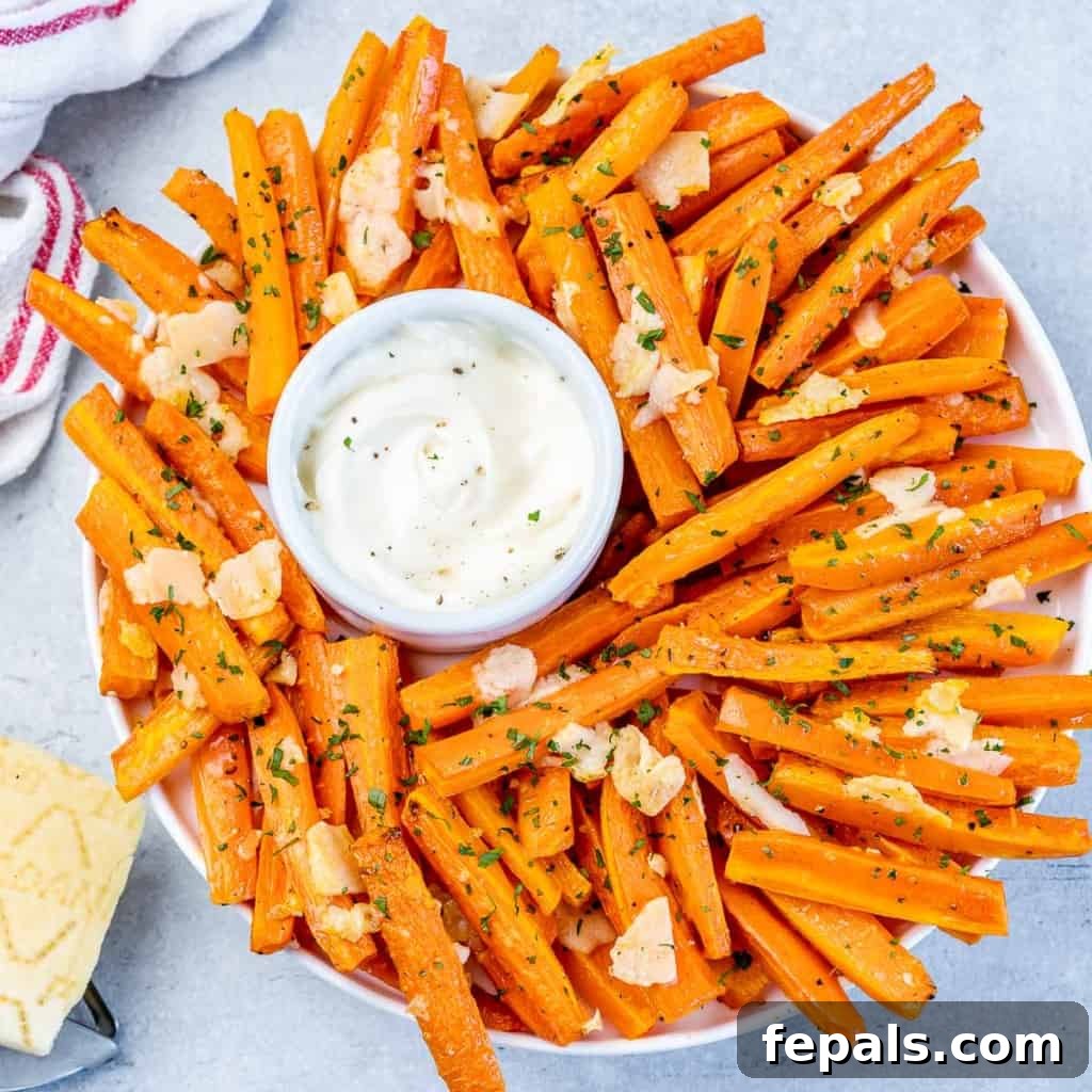 Parmesan Crusted Carrot Fries 10 Top view of roasted carrot fries beautifully arranged in a round plate, with a small bowl of creamy dipping sauce positioned centrally, ready for serving.
