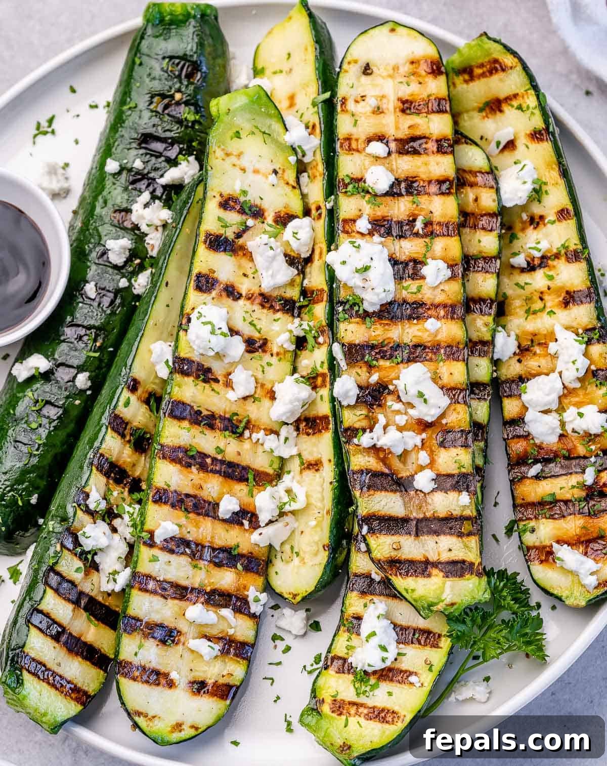 Closeup view of grilled zucchini topped with goat cheese.