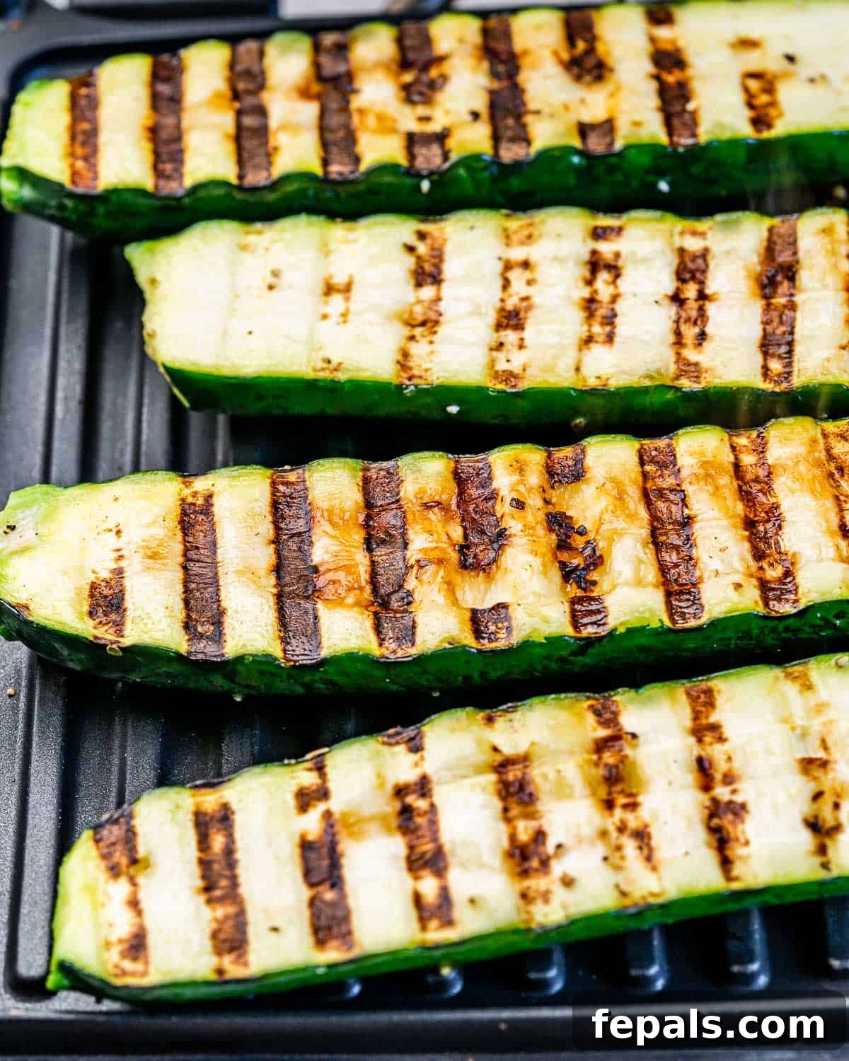 Zucchini halves on a grill with char marks.