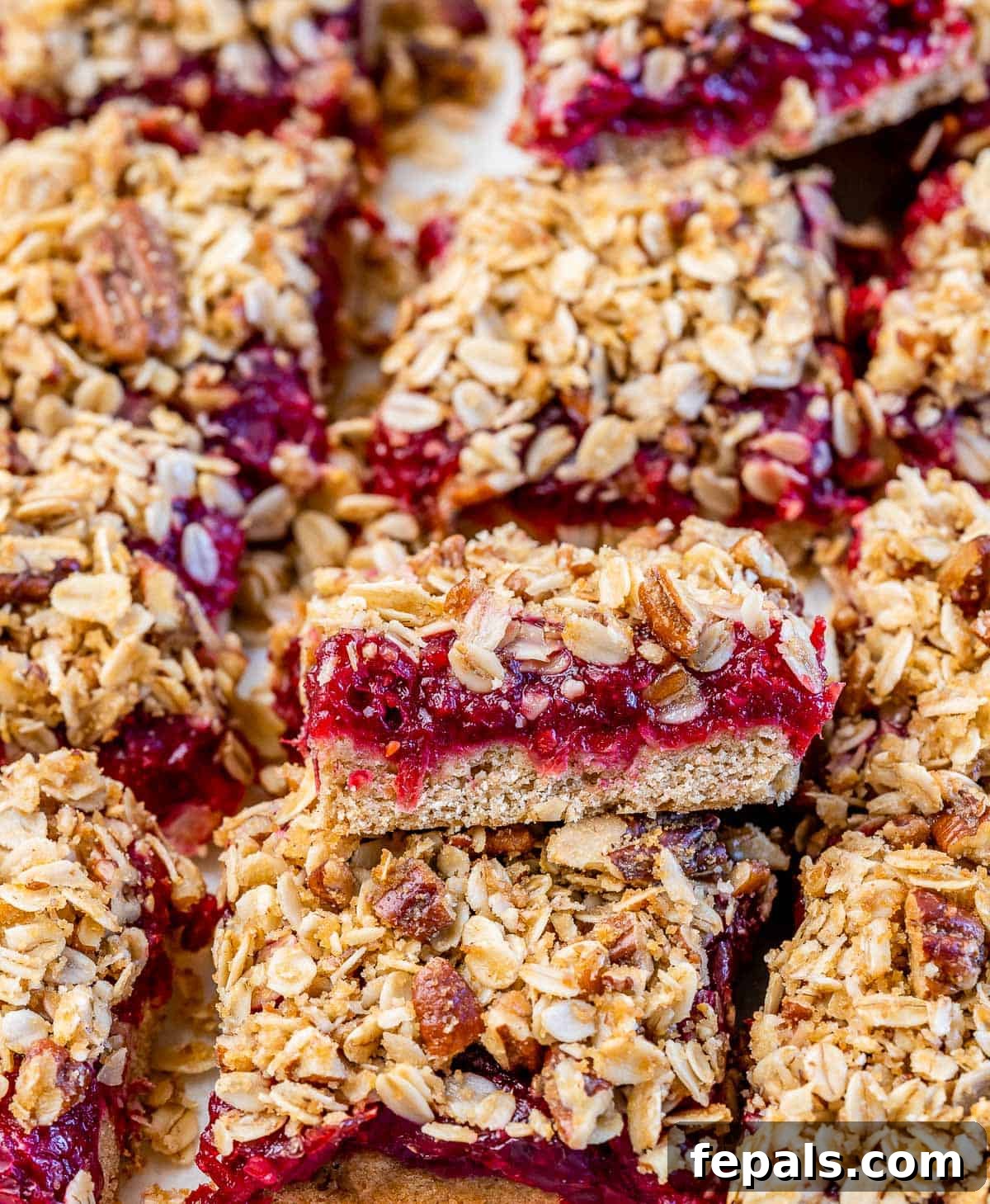 Cranberry bars with a golden pecan crumble topping, showcasing the vibrant cranberry filling peeking through.