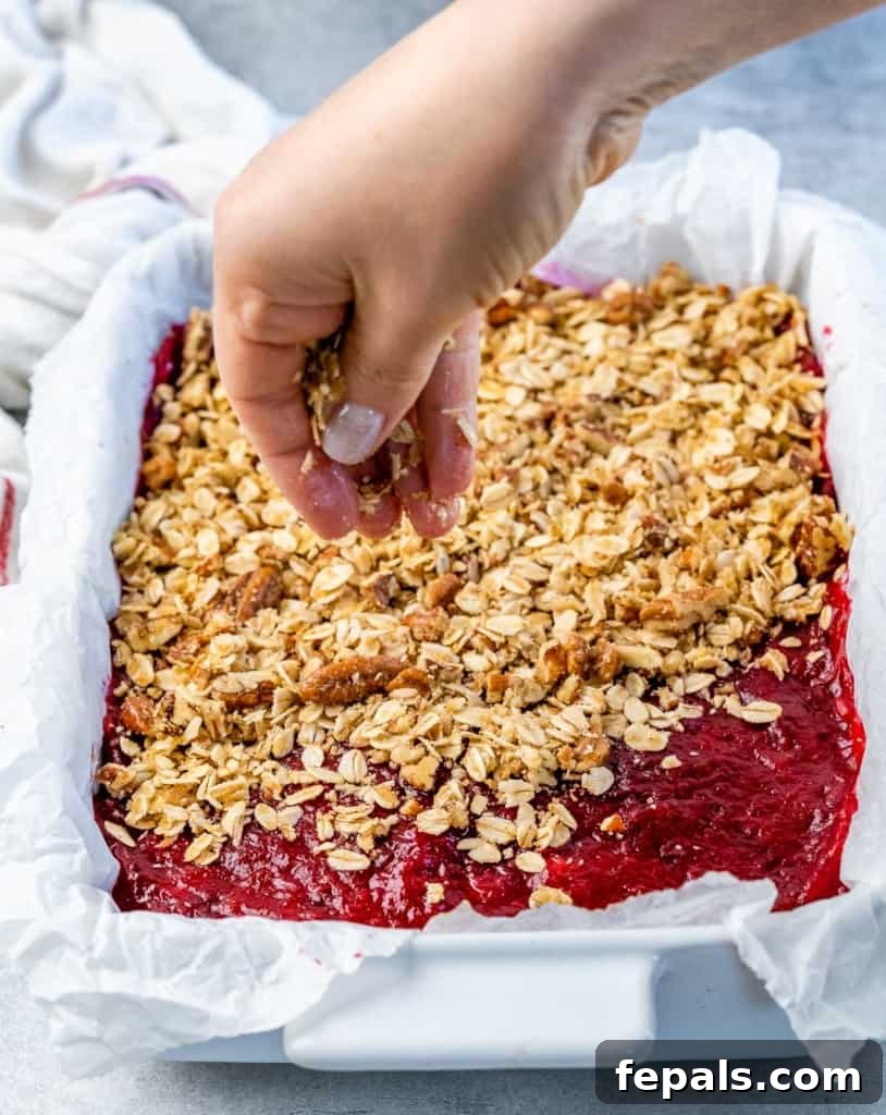 Sprinkling crumbly oat topping over a vibrant layer of cranberry sauce.