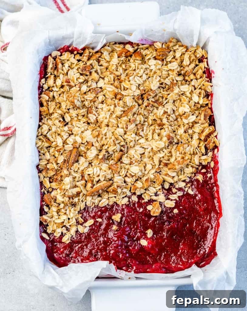 Assembling cranberry bars, showing the final layers of crust, cranberry, and oat topping before baking.