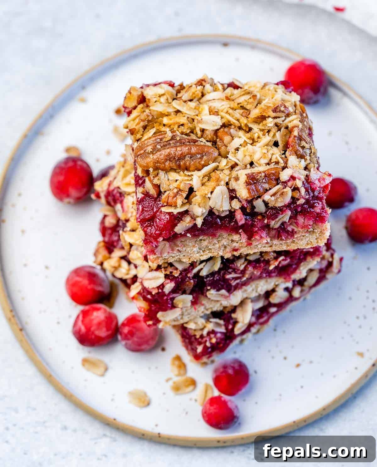 Cranberry bars stacked neatly on a white plate, ready for serving.