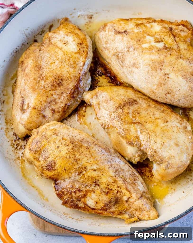 Searing chicken breasts in a hot cast iron skillet to create a golden crust.