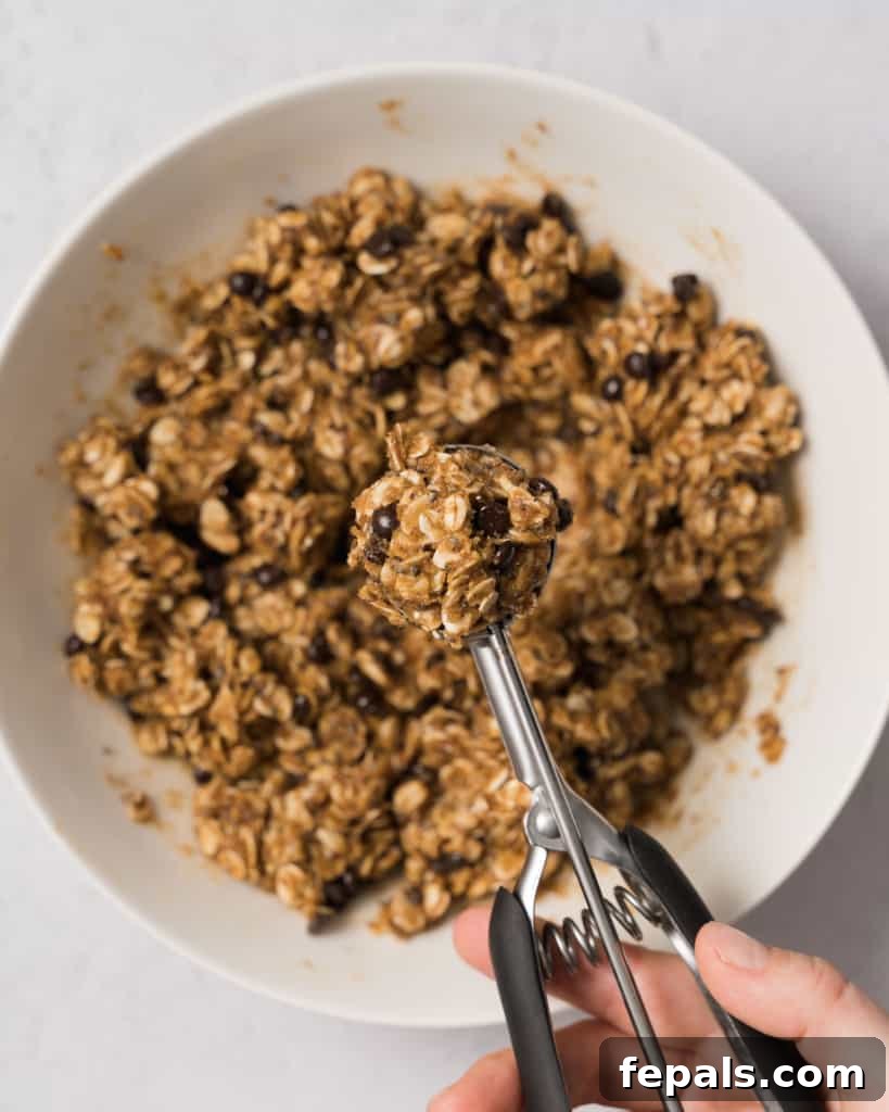 Spiced Pumpkin Power Morsels 12 A cookie scoop portioning out the pumpkin energy bite dough onto a surface.