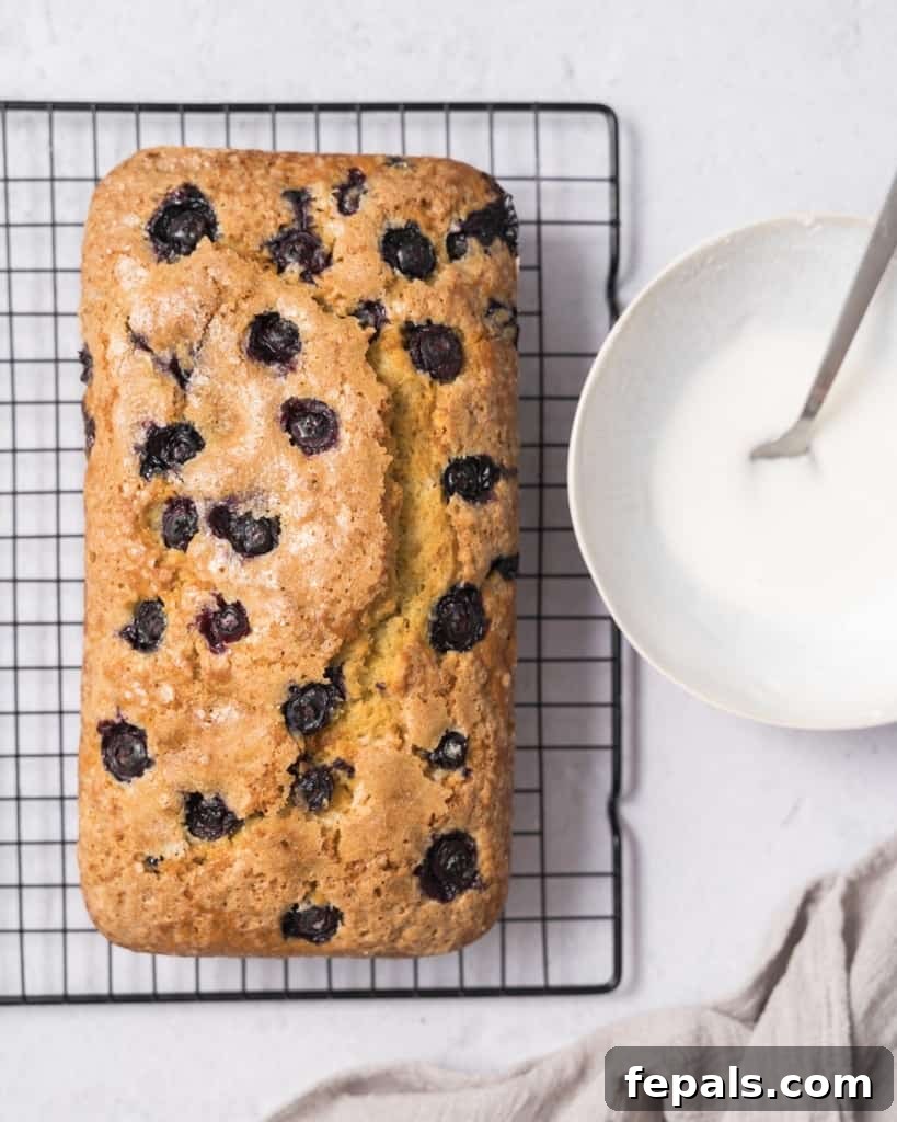 Zesty Blueberry Lemon Loaf 18 icing glaze next to blueberry bread on wire wrack