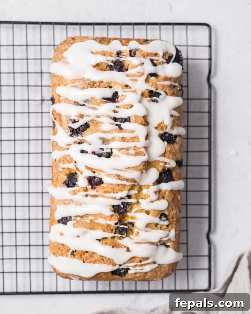 Zesty Blueberry Lemon Loaf 3 top view of a lemon loaf bread with glaze and placed on a wire wrack