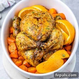 Maple-Kissed Roasted Whole Chicken 12 top view of a whole baked chicken over chopped carrots in a white dish