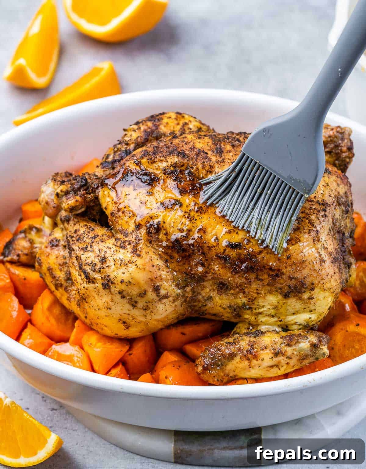 Maple-Kissed Roasted Whole Chicken 7 Basting a whole baked chicken with maple glaze in a baking dish.