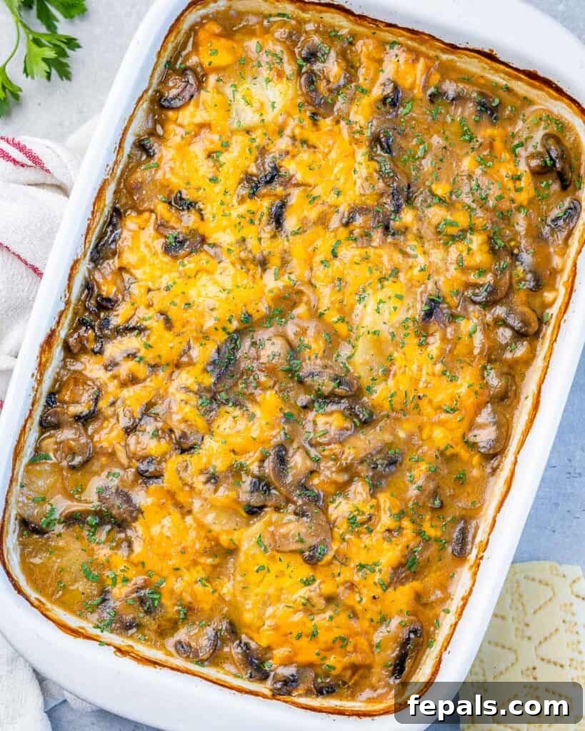 Top-down view of a golden-yellow, cheesy potato and mushroom casserole in a pristine white baking dish, ready to be served.