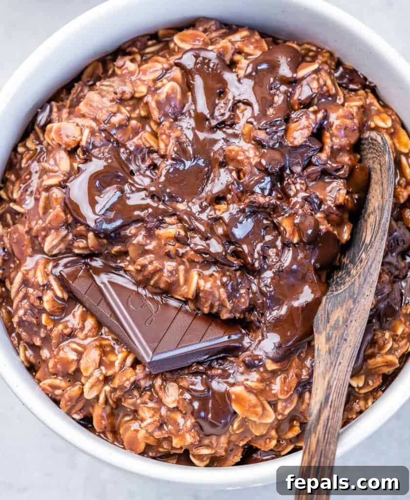 Decadent Cocoa Oat Delight 2 top view bowl of creamy chocolate oatmeal with brown wooden spoon in the bowl, topped with melted chocolate
