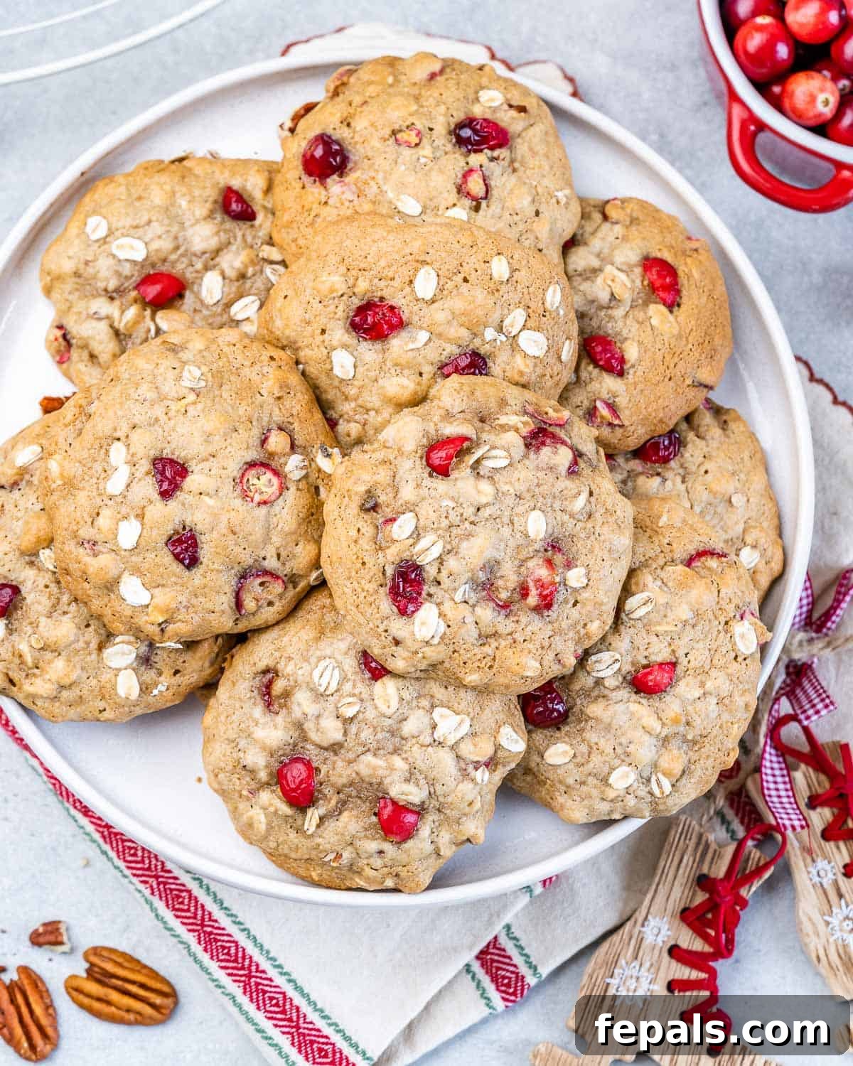 Top view of cranberry oatmeal cookies spread over each other on a white round plate.