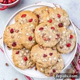 top view of cranberry oatmeal cookies spread over each other on a white round plate