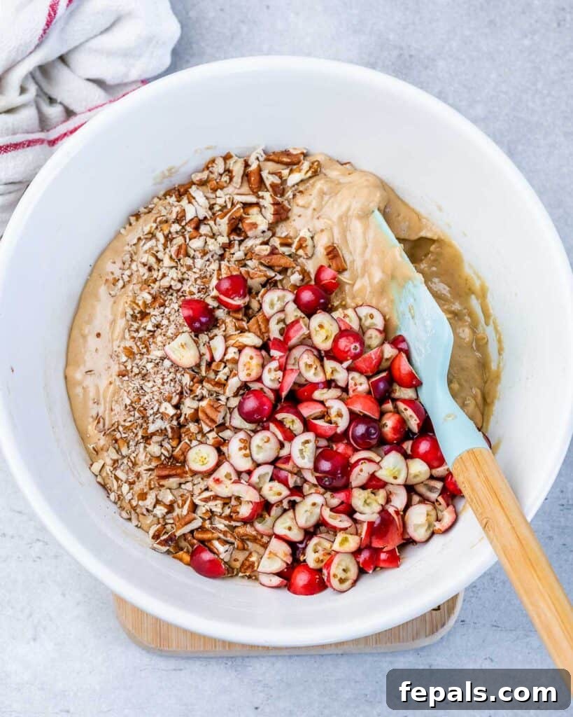 Stirring cranberries and pecans into cookie dough.