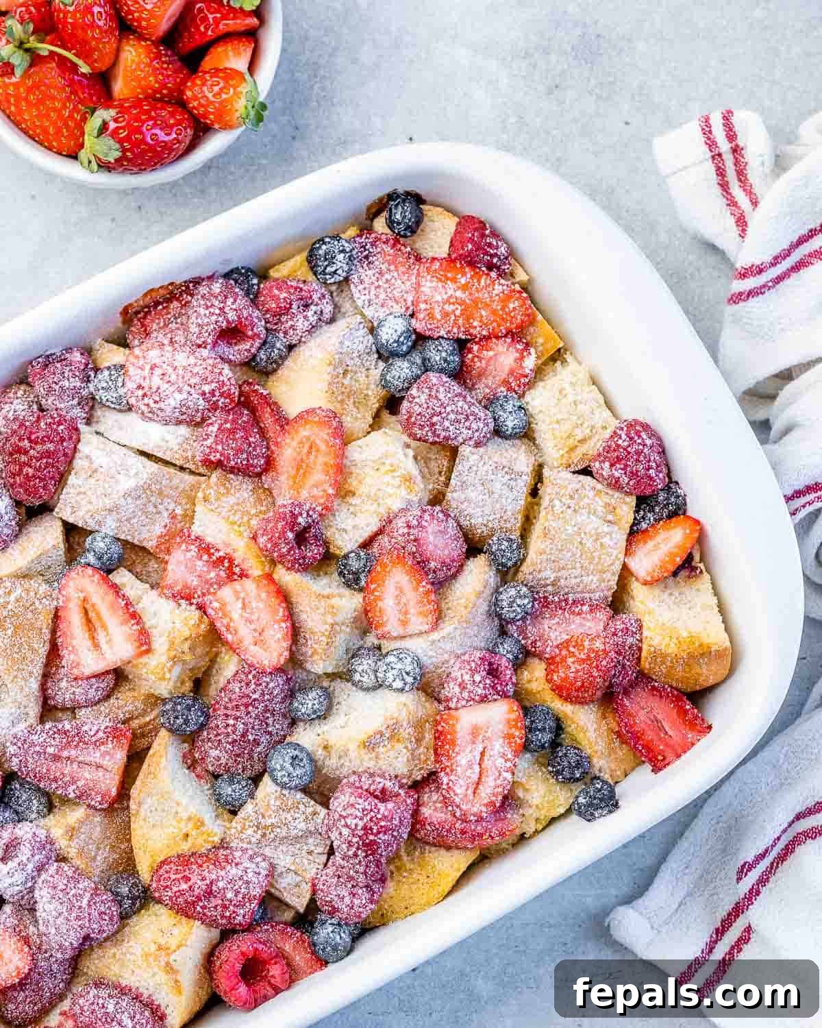 French toast casserole topped with berries and powdered sugar, ready to be served.