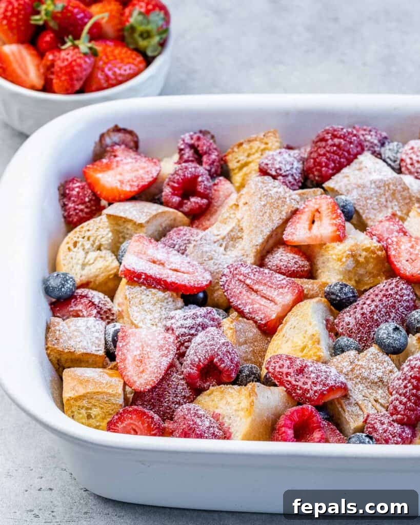 Baked French toast casserole topped with berries and powdered sugar, fresh out of the oven.