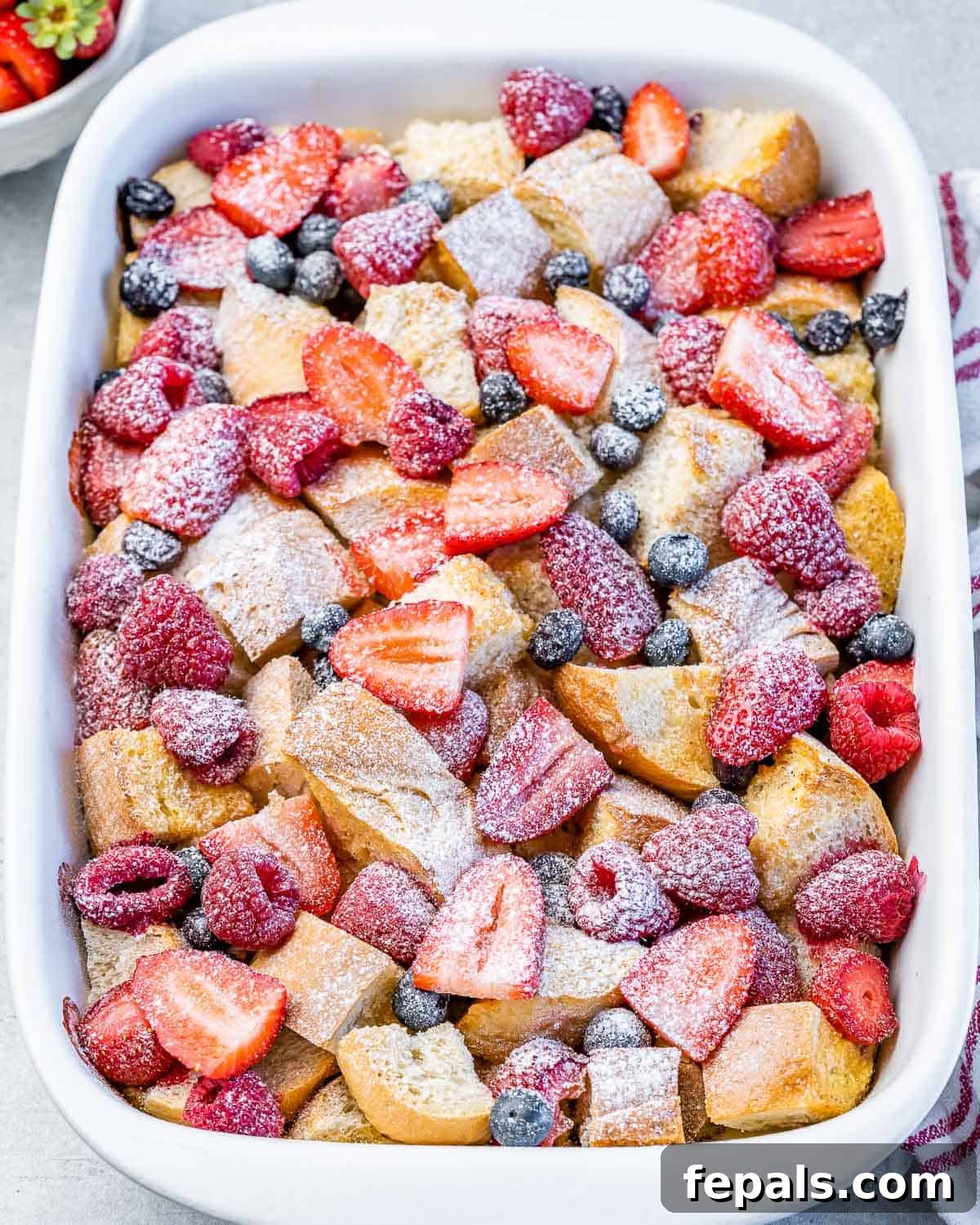 Berries French toast casserole in a white baking dish, ready for serving.