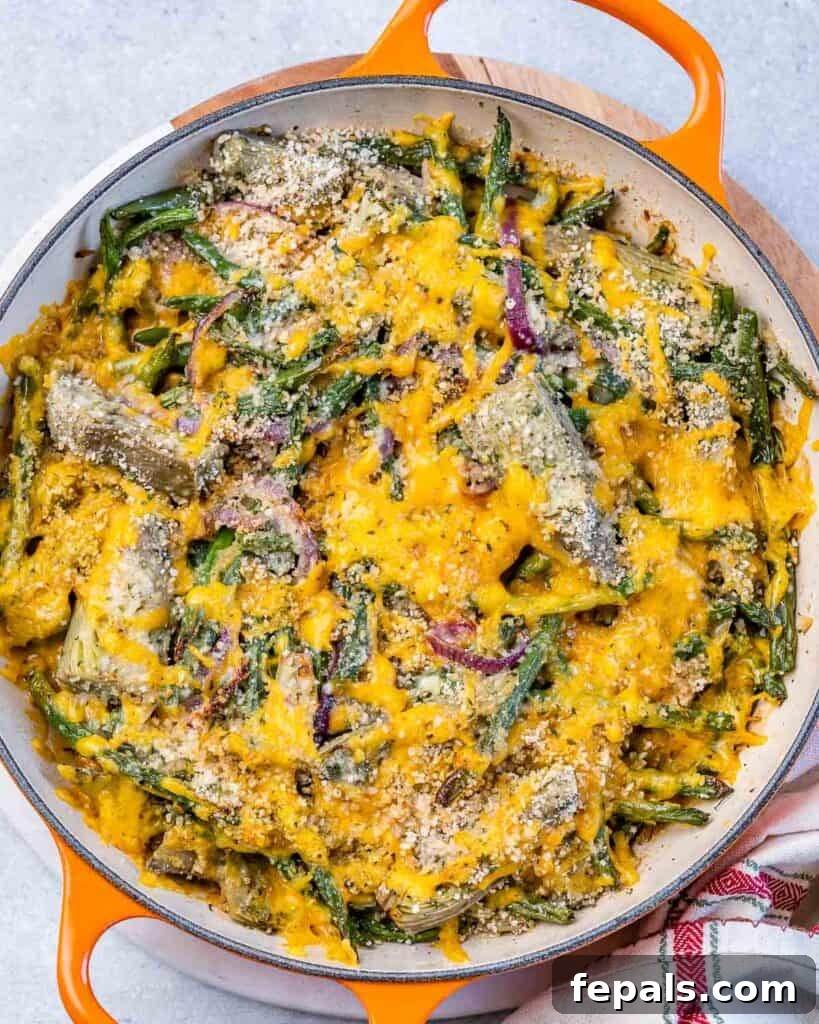 Mediterranean Artichoke Green Bean Bake 9 top view of an orange skillet with green beans and artichoke casserole that is topped with melted cheddar cheese