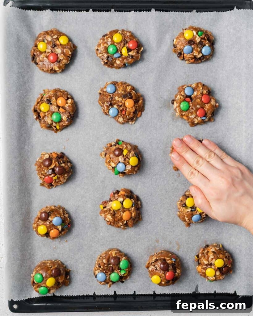 Gently pressing down on cookie dough balls to slightly flatten them for thinner cookies.