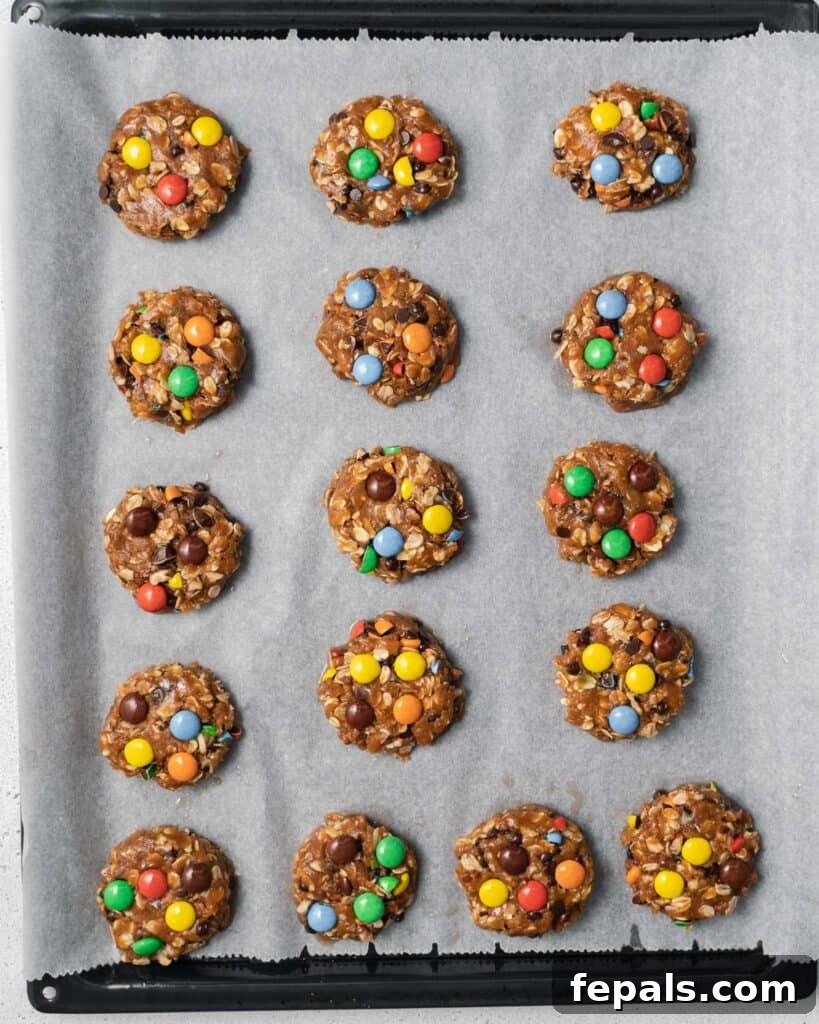 Flattened monster cookie dough on a baking pan, ready for the oven.