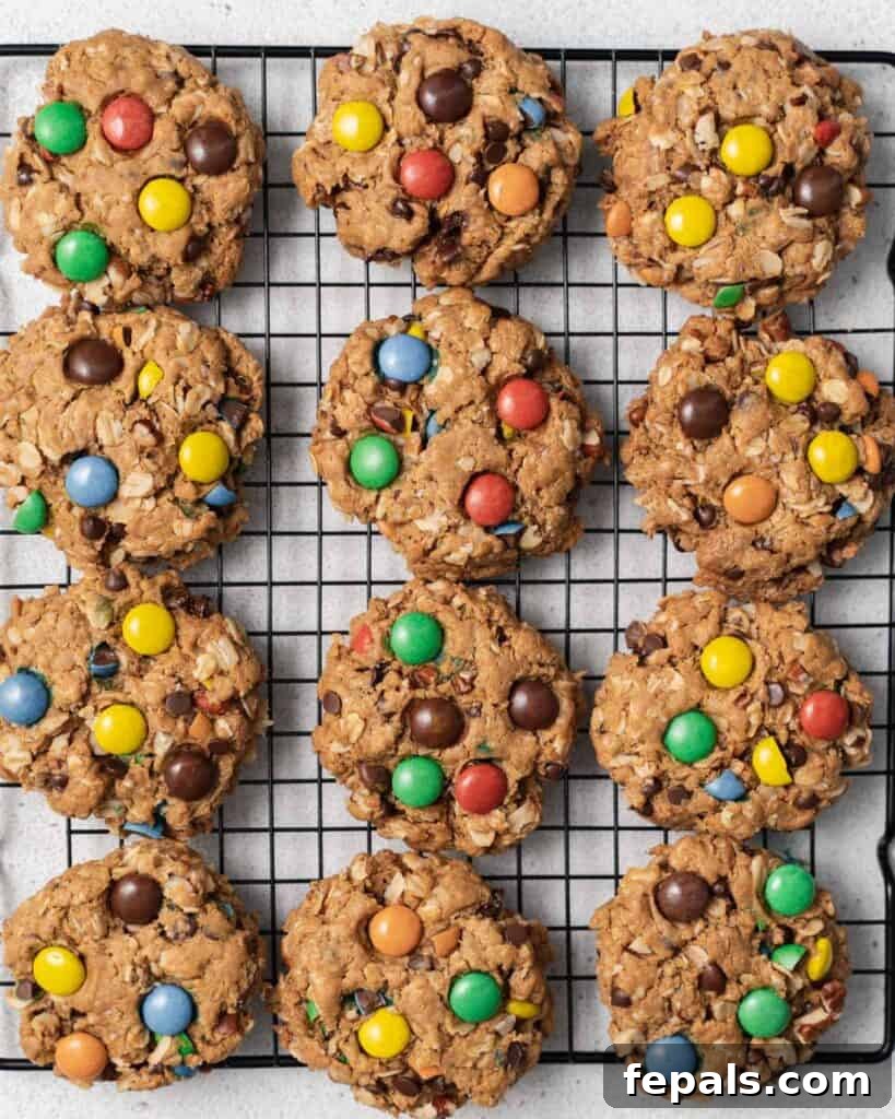Freshly baked monster cookies cooling on a wire rack, glistening with melted chocolate.