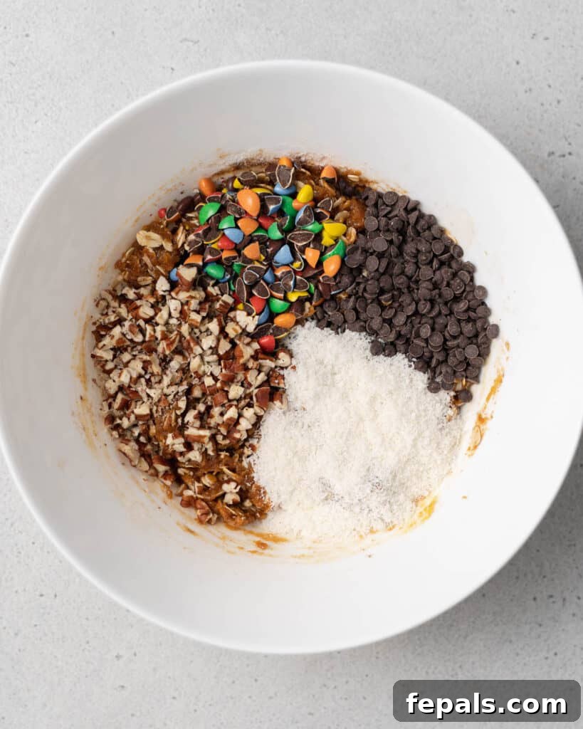Adding mini M&M's, chocolate chips, chopped nuts, and shredded coconut to the oat mixture.