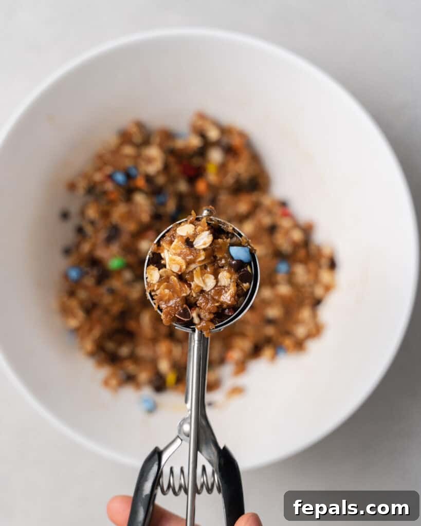 A perfectly rounded scoop of cookie dough resting on a cookie scoop.