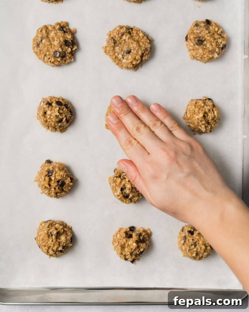 Wholesome Western Wonders 14 Gently pressing on cookie dough balls on a baking sheet to flatten it slightly for baking Healthy Cowboy Cookies.