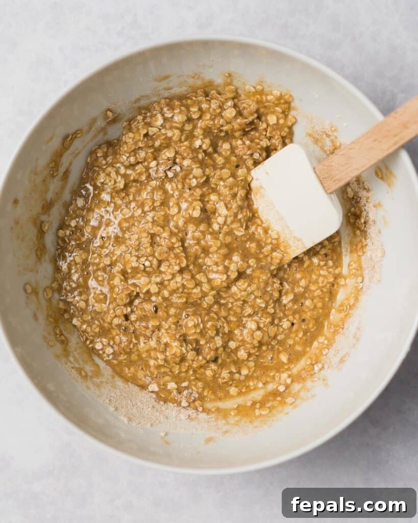 Wholesome Western Wonders 10 Stirring together wet and dry ingredients with a spatula to form cowboy cookie dough.