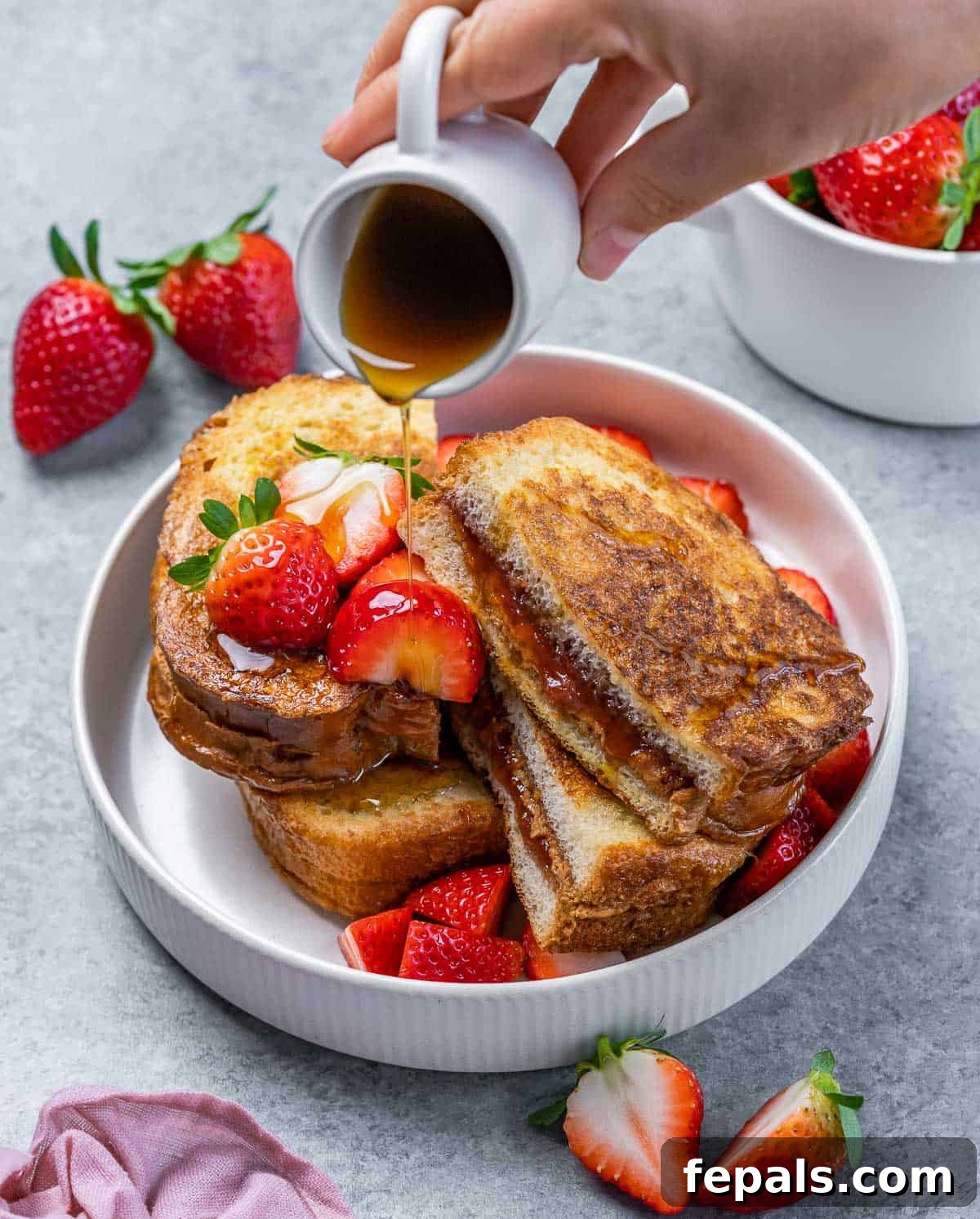 Peanut Butter Jelly French Toast Surprise 3 Drizzling maple syrup over the top of stuffed French toast.