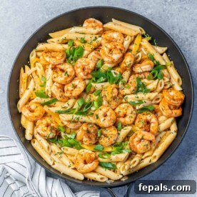 Top view black skillet with shrimp and penne pasta