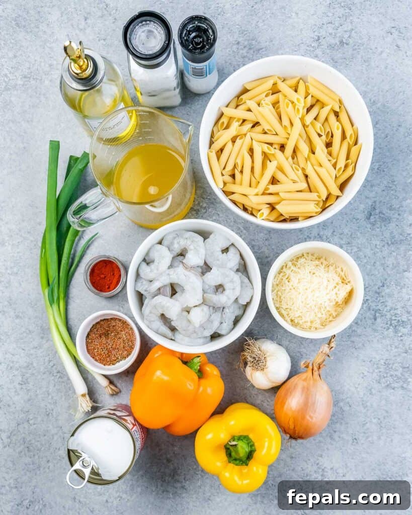Various ingredients for Jamaican Shrimp Rasta Pasta laid out on a flat surface, including shrimp, penne pasta, bell peppers, onions, and seasonings.