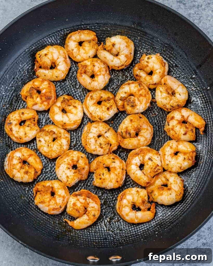 Cooked, seasoned shrimp in a black skillet, before the pasta and sauce are added.