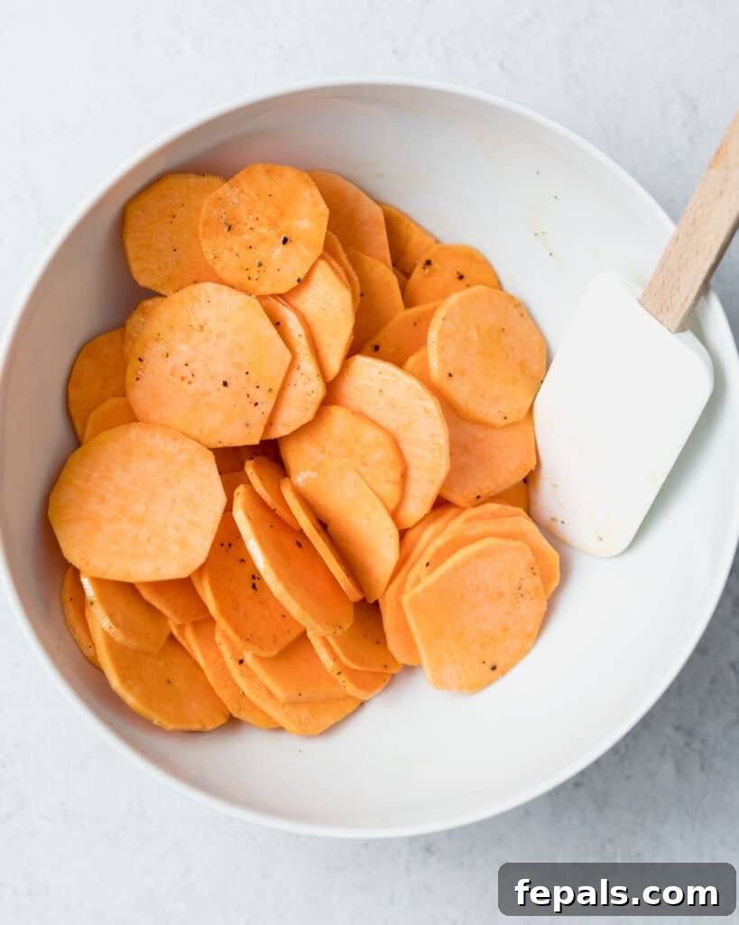 Crispy Air-Fried Sweet Potato Crisps 8 spatula mixing the sliced potatoes in a bowl