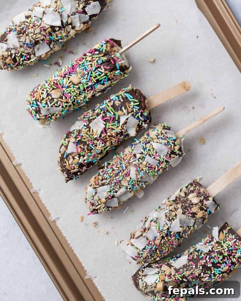 Frozen Chocolate Banana Bites 13 banana pops topped with sprinkles over parchment paper